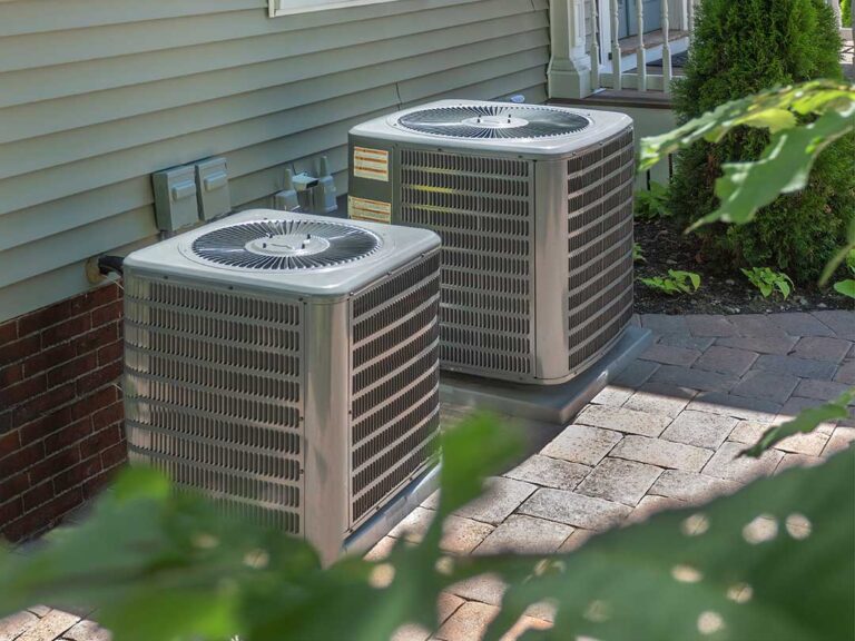 Technician inspecting an indoor air conditioner beside a thermostat and return vent in a home.